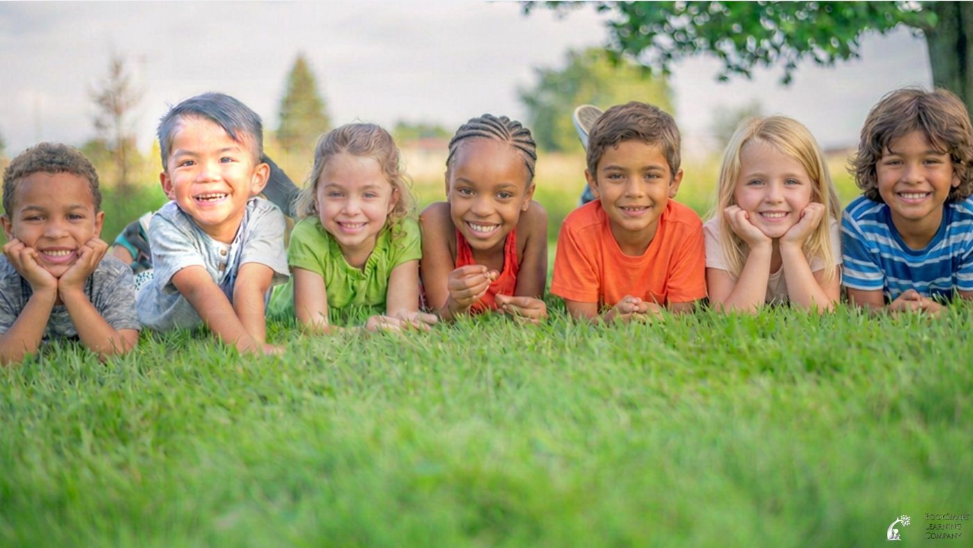 Happy, smiling kids lying in the grass — fun reading journals, classroom resources and creative notebooks for children in kindergarten through grade 6